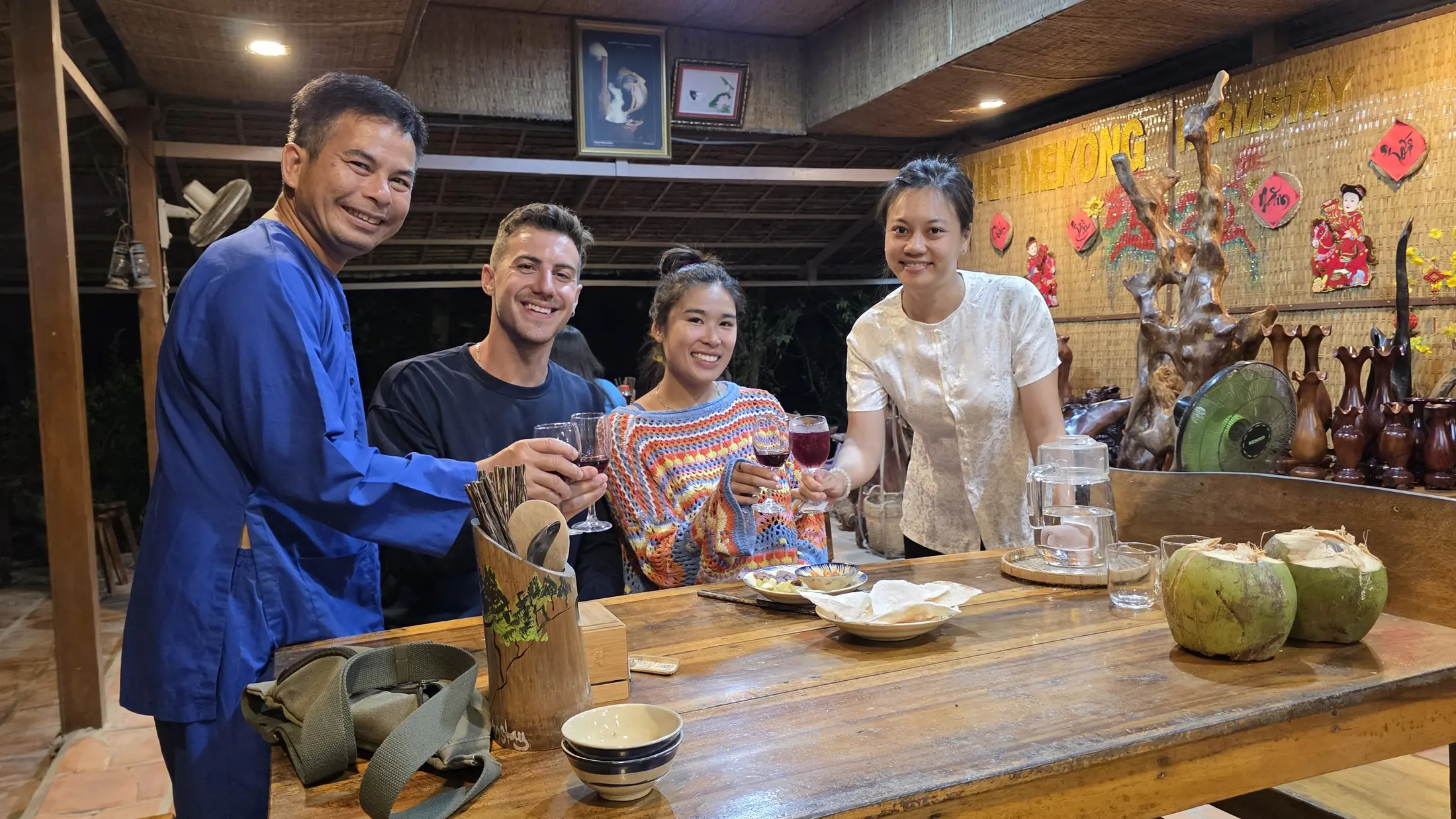 Adult guests and their host sharing food and fresh coconuts