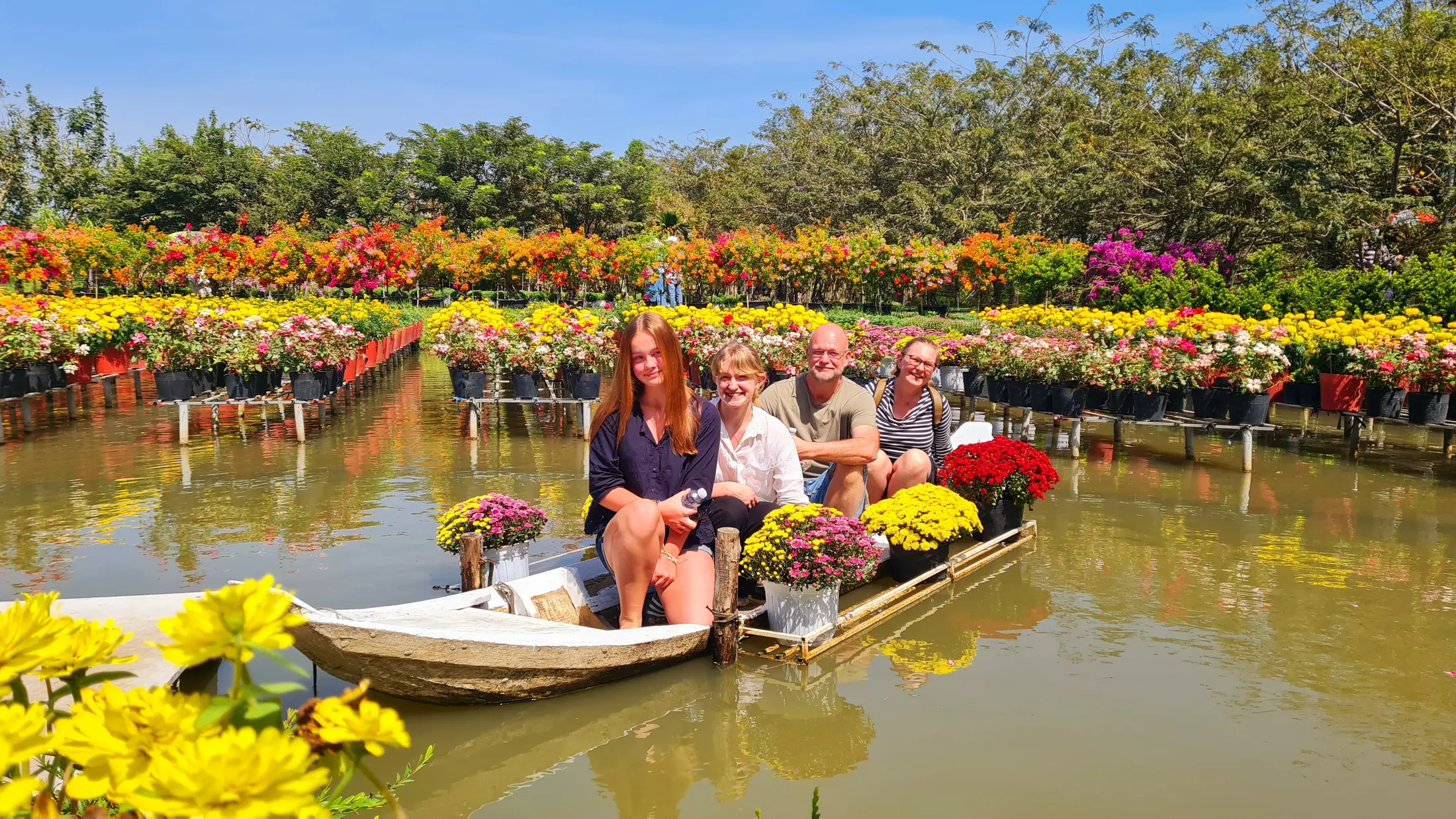 Visitors in a small boat among flower beds in Sa Dec