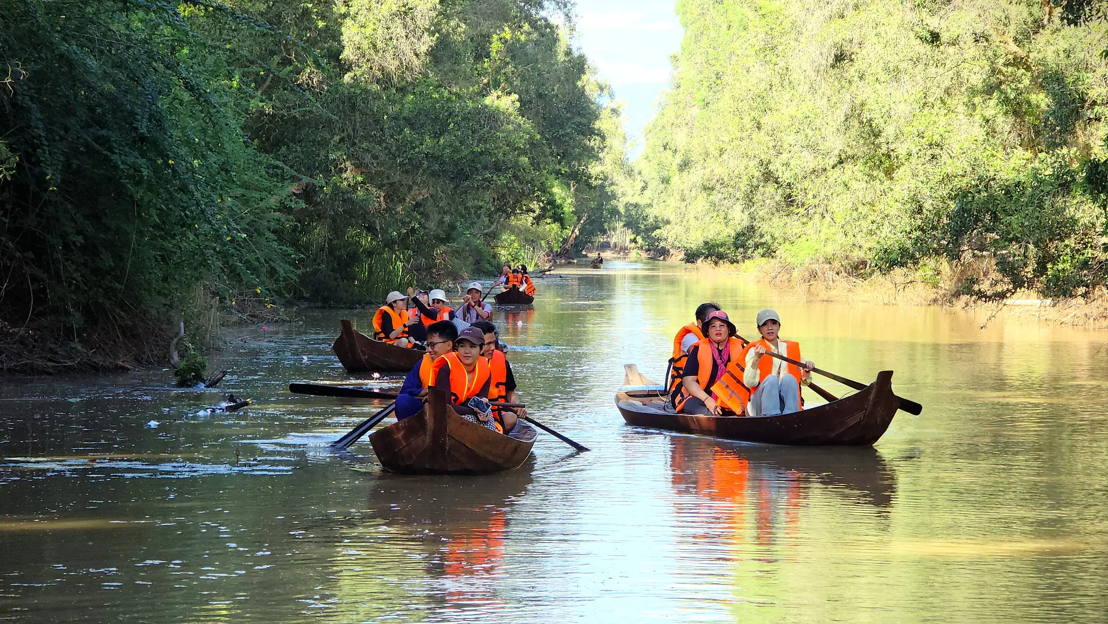 Visitors travelling quietly by rowing boat through a shaded waterway