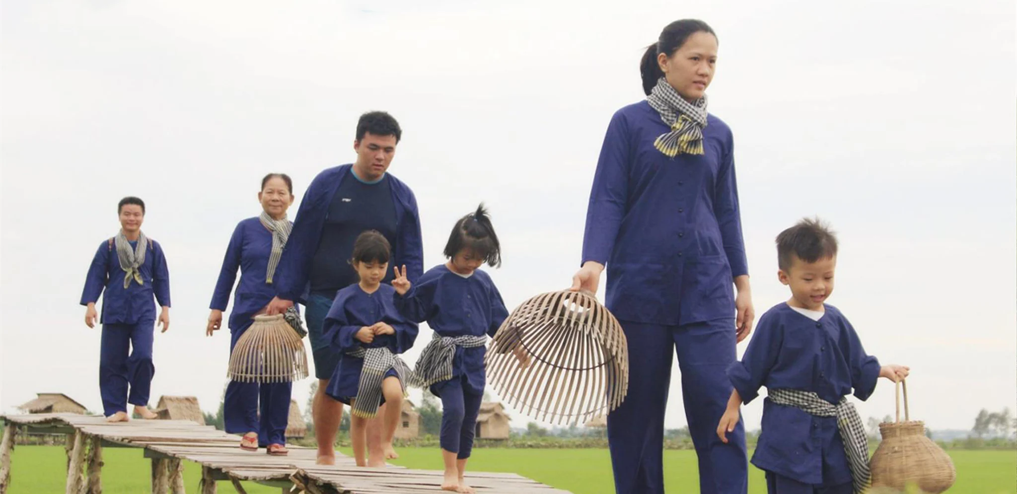 Visitors walking on a wooden boardwalk through the Viet Mekong Farmstay landscape